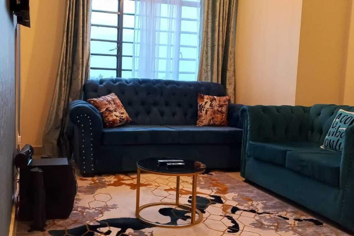 A living room with a dark blue sofa, a green sofa, a patterned rug, and a small round table.