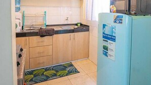 Una cocina compacta con microondas, un lavamanos y armarios de madera.