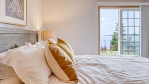 Habitación de hotel con una cama, ventana con vistas al exterior y un cuadro en la pared.