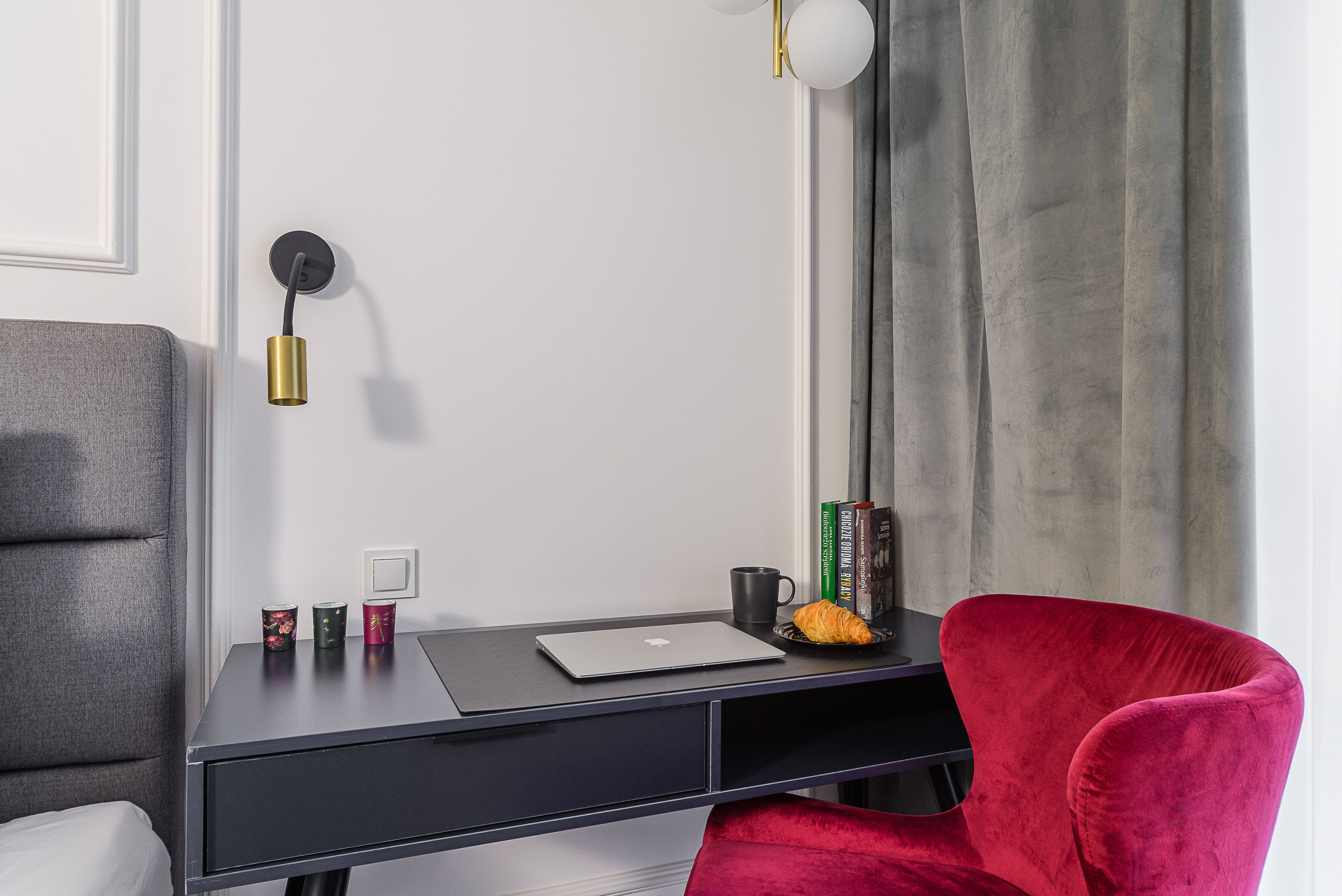 A modern workspace with a desk, laptop, and a red chair.