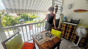A balcony with a table set for two, a fan, and a sign reading "Ti Punch BAR". - Studio tout confort dans son écrin de verdure au pieds de la Marina (Saint-François)