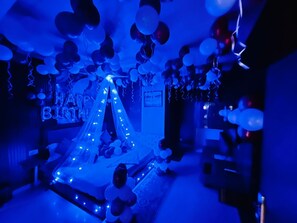 A room decorated with balloons and lights, with a 'Happy Birthday' sign. - Hotel Grand Inn (New Delhi)