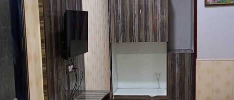 A bedroom with a bed, a red rug, a TV, and a wall-mounted air conditioner.