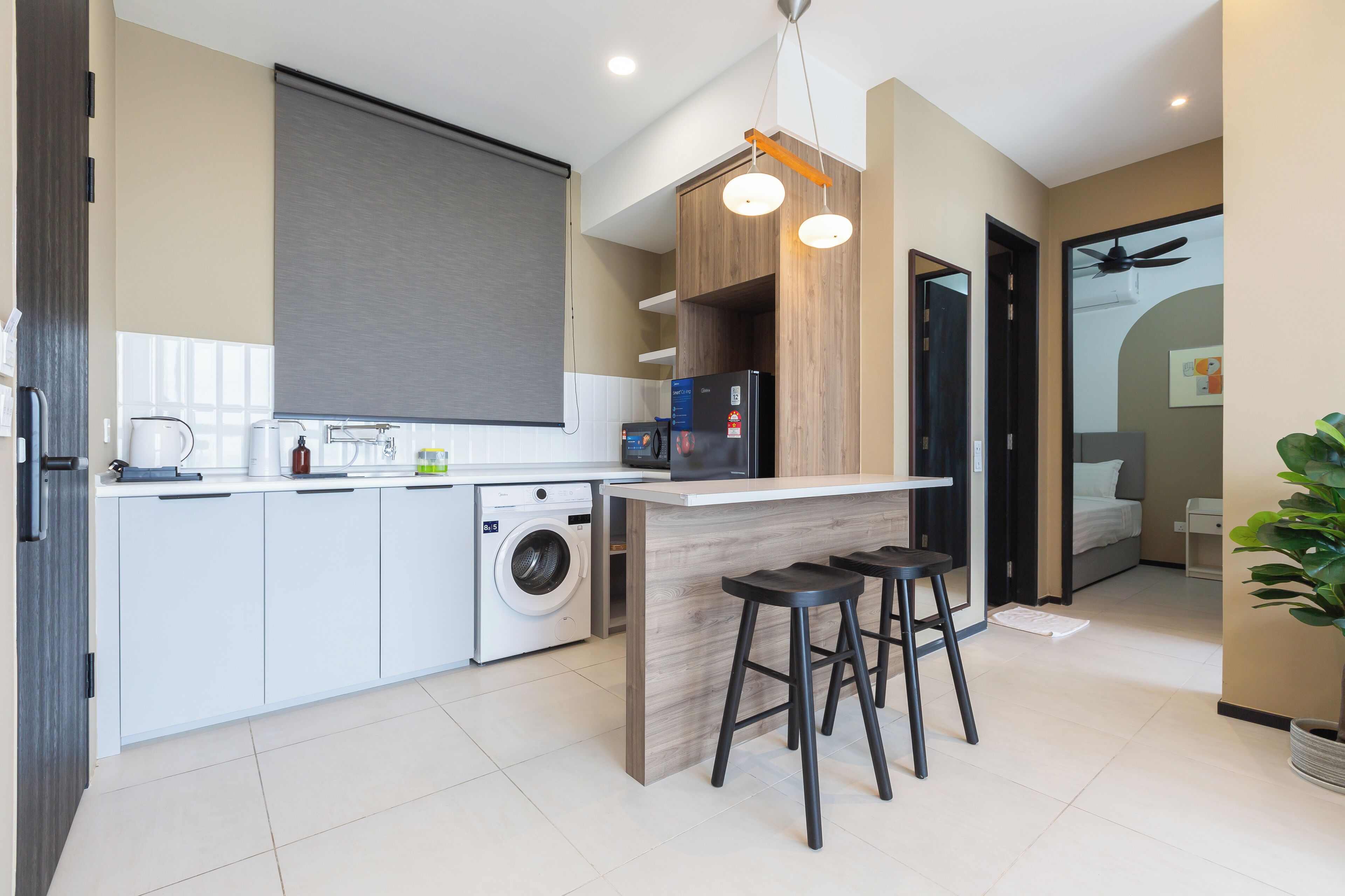 A modern kitchen with a built-in washing machine, a bar area with stools, and a ceiling fan.