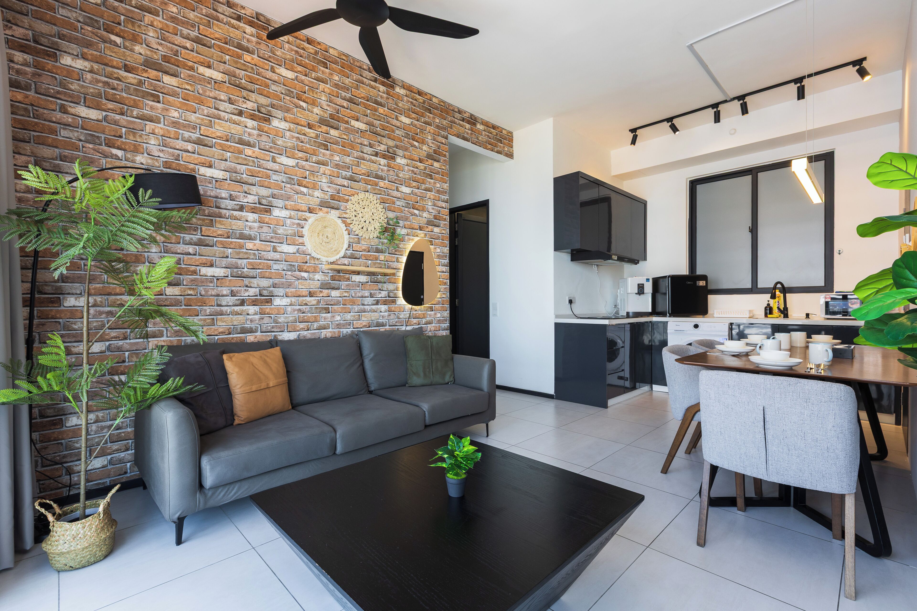 Ein modernes Wohnzimmer mit grauem Sofa, einem schwarzen Couchtisch und einer Ziegelwand.