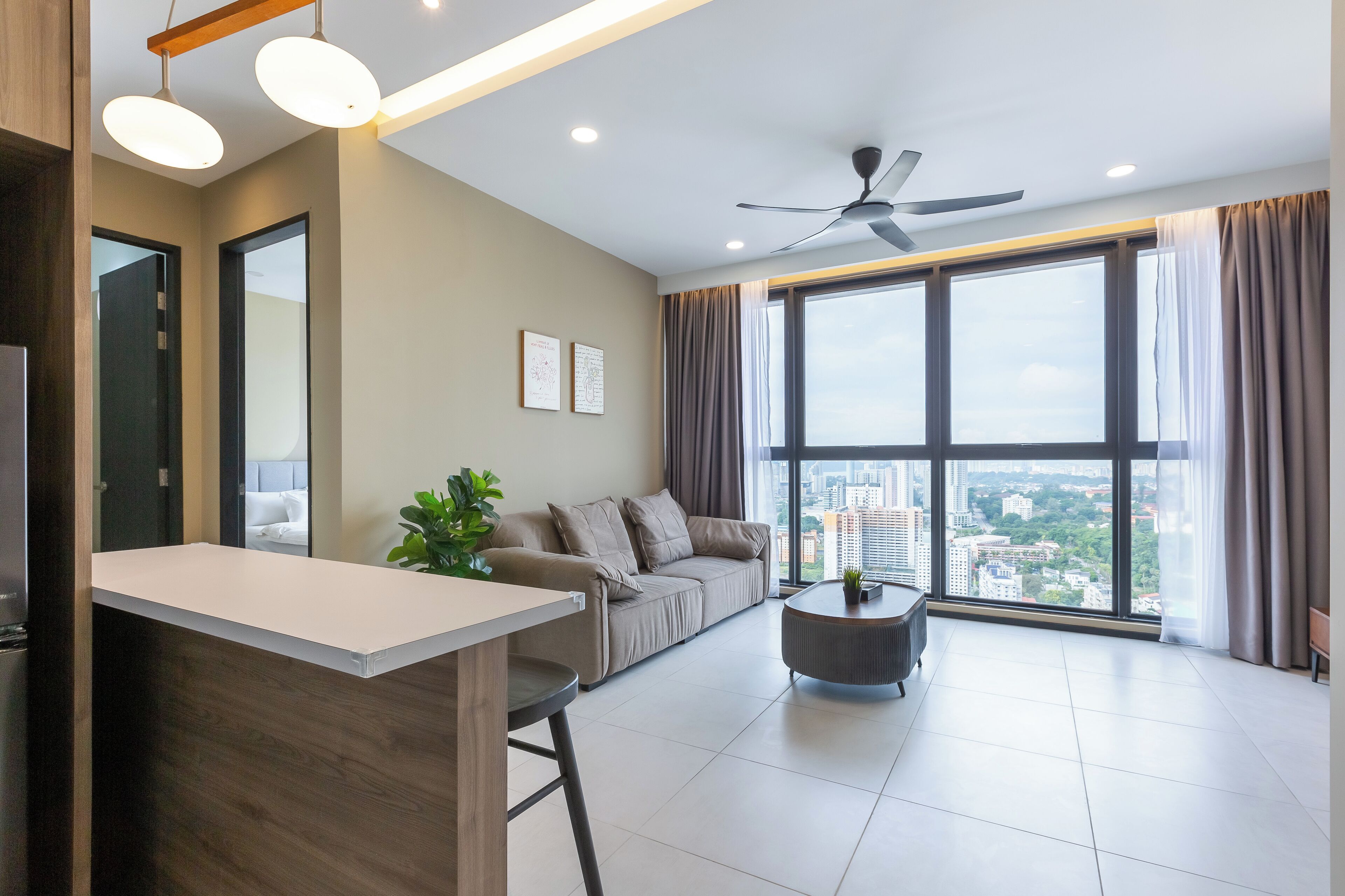A modern living room with a sofa, a coffee table, and a view of the city through large windows.