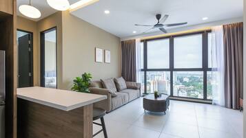 A modern living room with a sofa, a coffee table, and a view of the city through large windows.