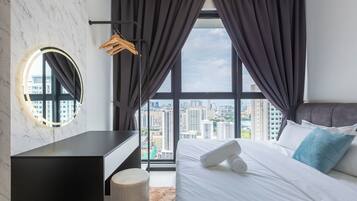 Quarto moderno com vista para a cidade, espelho redondo, mesa de cabeceira e cama com roupa de cama branca e almofada azul.