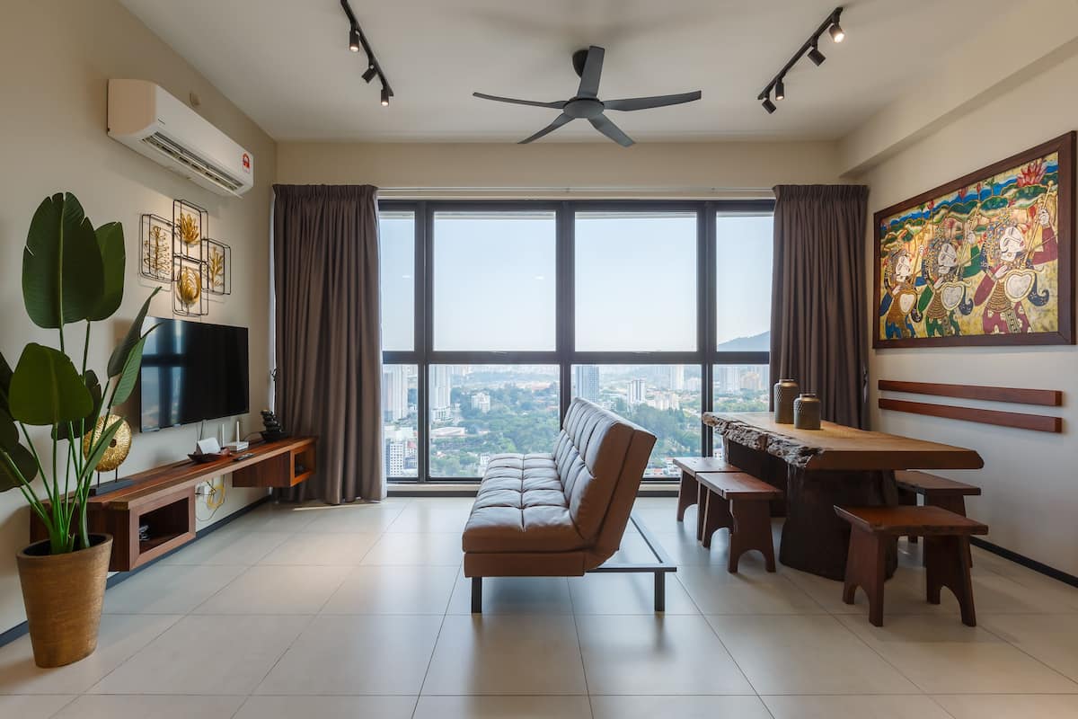 A modern living room with a sofa, TV, dining table, and large windows offering a city view.