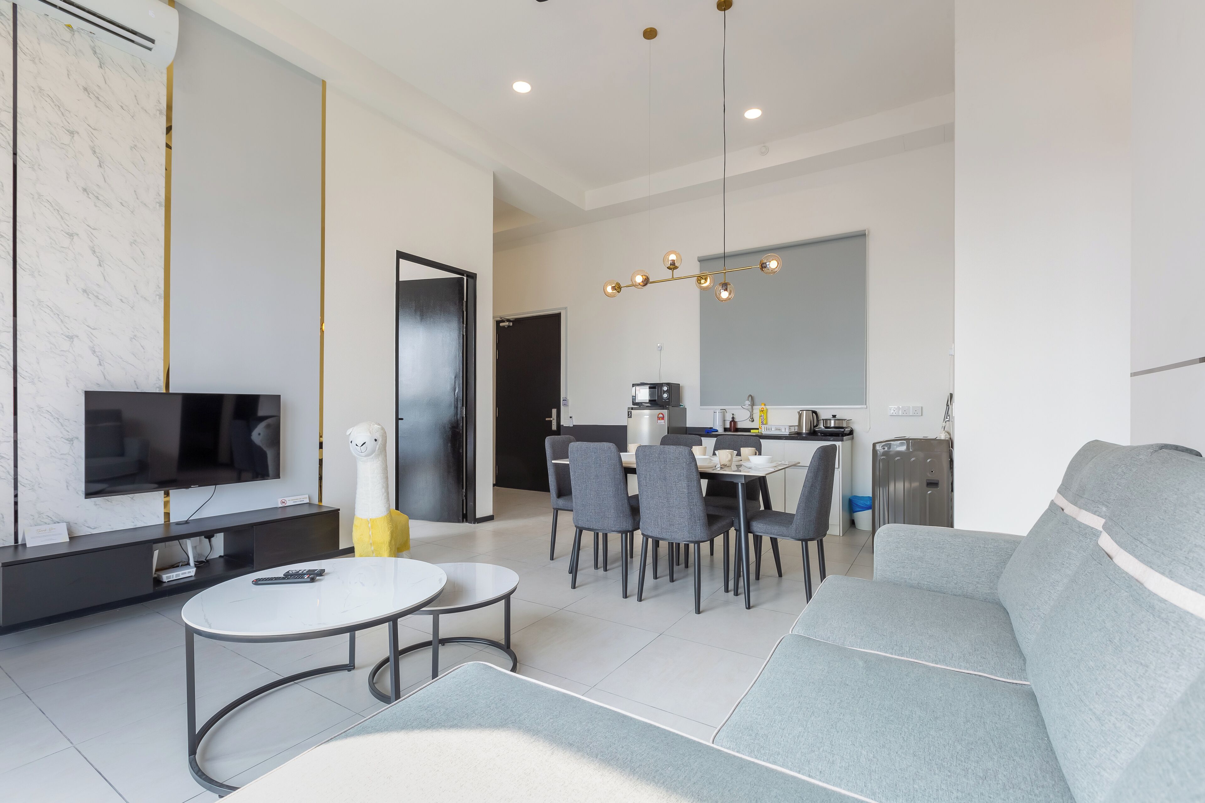 Een moderne woonkamer met een televisie, bank, eettafel en stoelen.