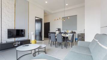Een moderne woonkamer met een televisie, bank, eettafel en stoelen.