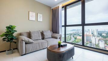 A modern living room with a sofa, a coffee table, and a large window offering a city view.