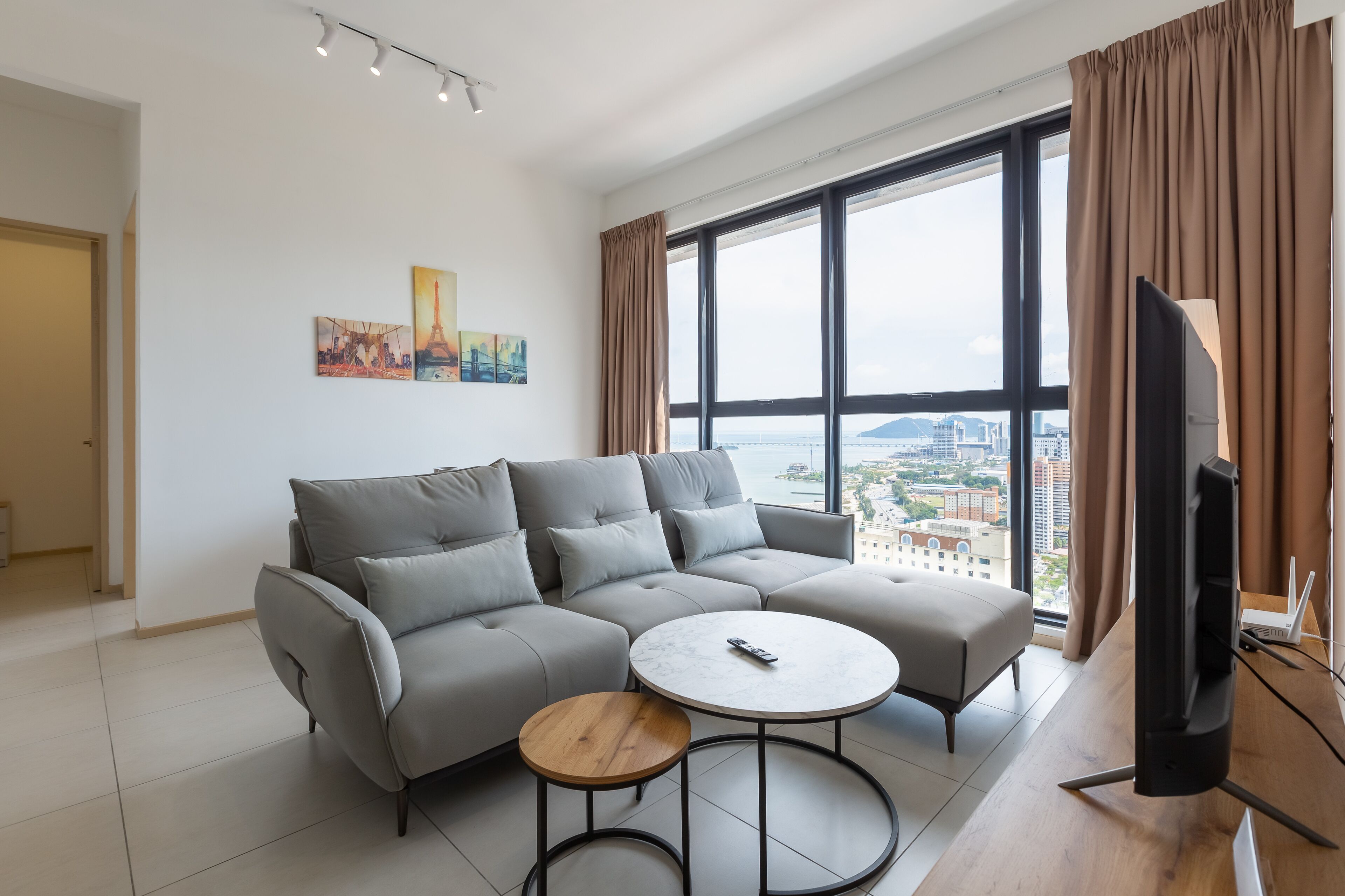 A modern living room with a grey sectional sofa, a round coffee table, and a television.