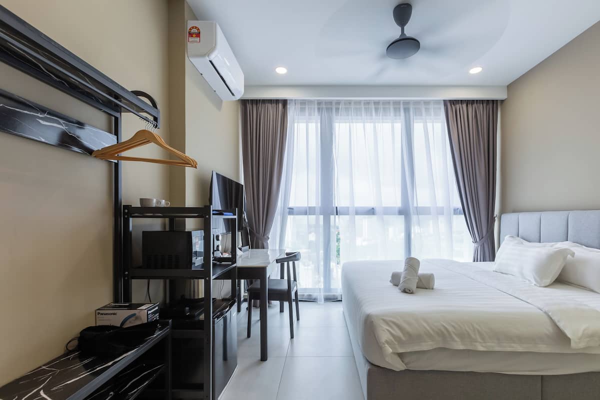 A hotel room with a bed, a desk with a chair, a TV, and a wardrobe.