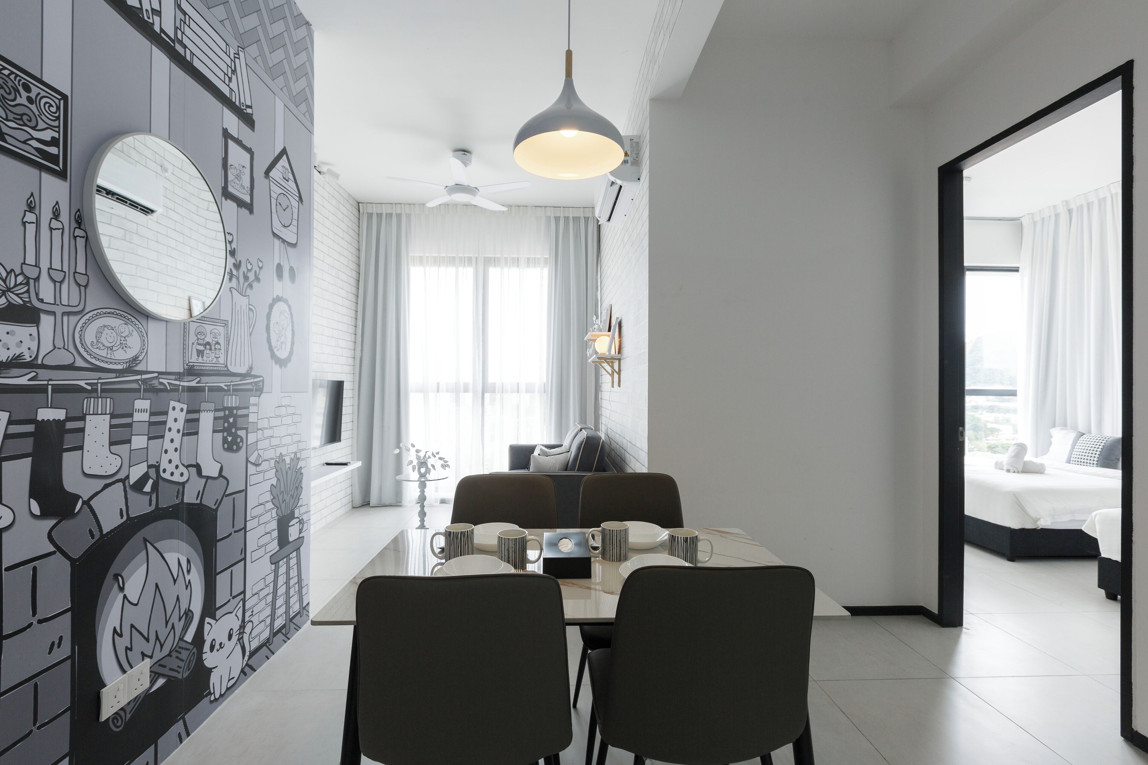 A modern dining area with a fireplace, a round mirror, and a dining table set for four.