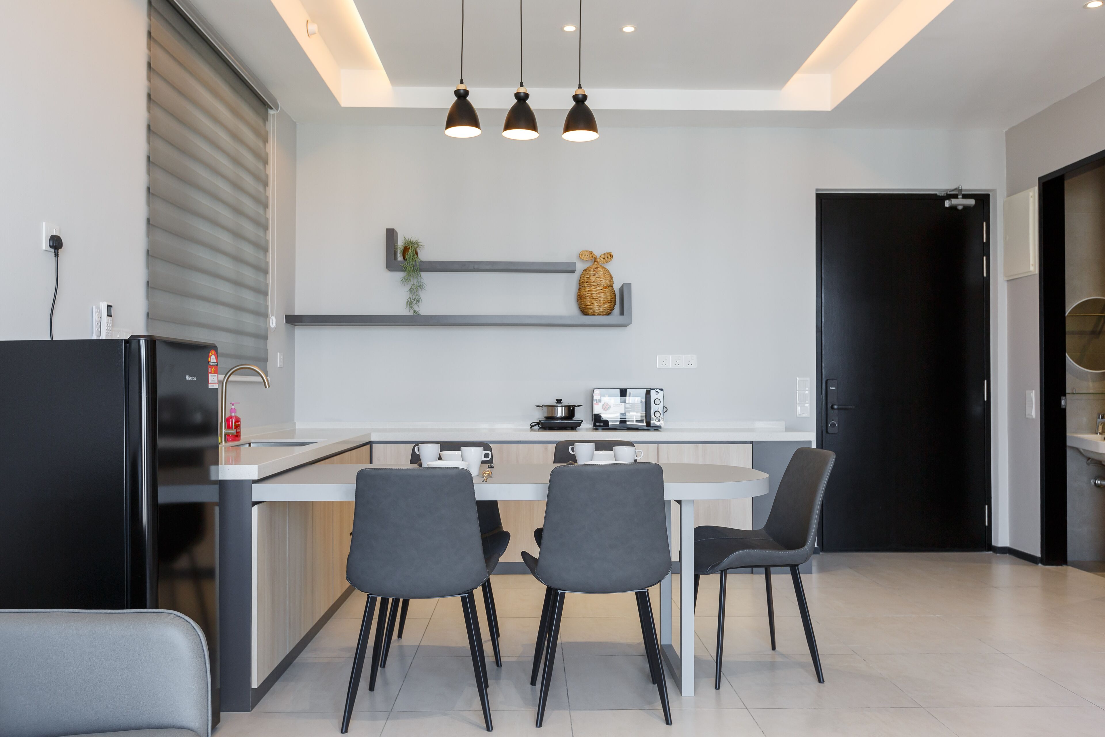 Una cocina moderna con una isla central, sillas grises e iluminación colgante.