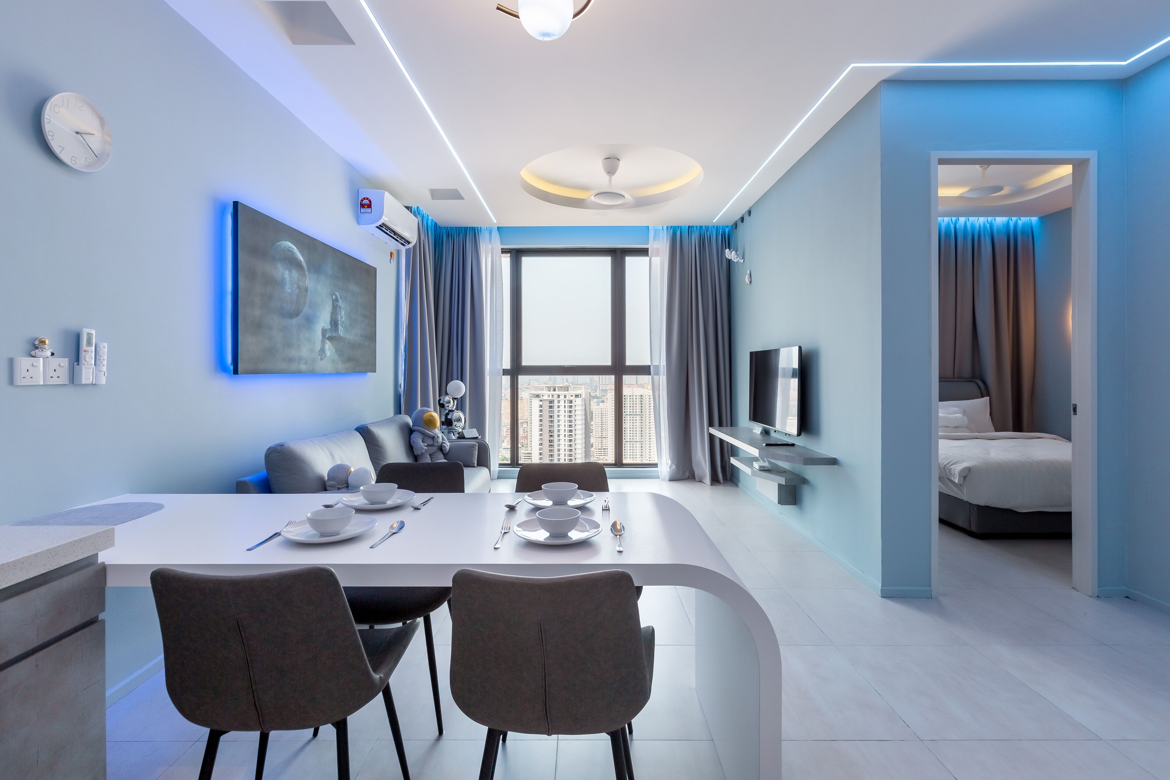 A modern hotel room with a dining area, a large window, and a separate bedroom.