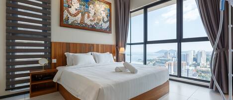 A hotel room with a large bed, a nightstand, a mirror, a painting, and a view of the city through large windows.