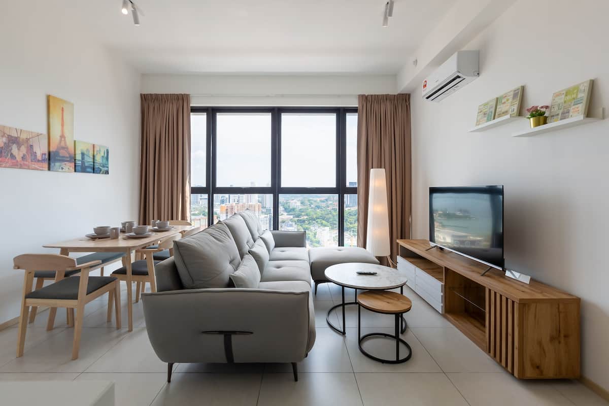 A modern living room with a sofa, dining table, chairs, a TV, and artwork on the walls.