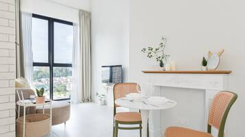 A modern living room with a dining area, large windows, and a view of the city.