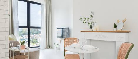 A modern living room with a dining area, large windows, and a view of the city.