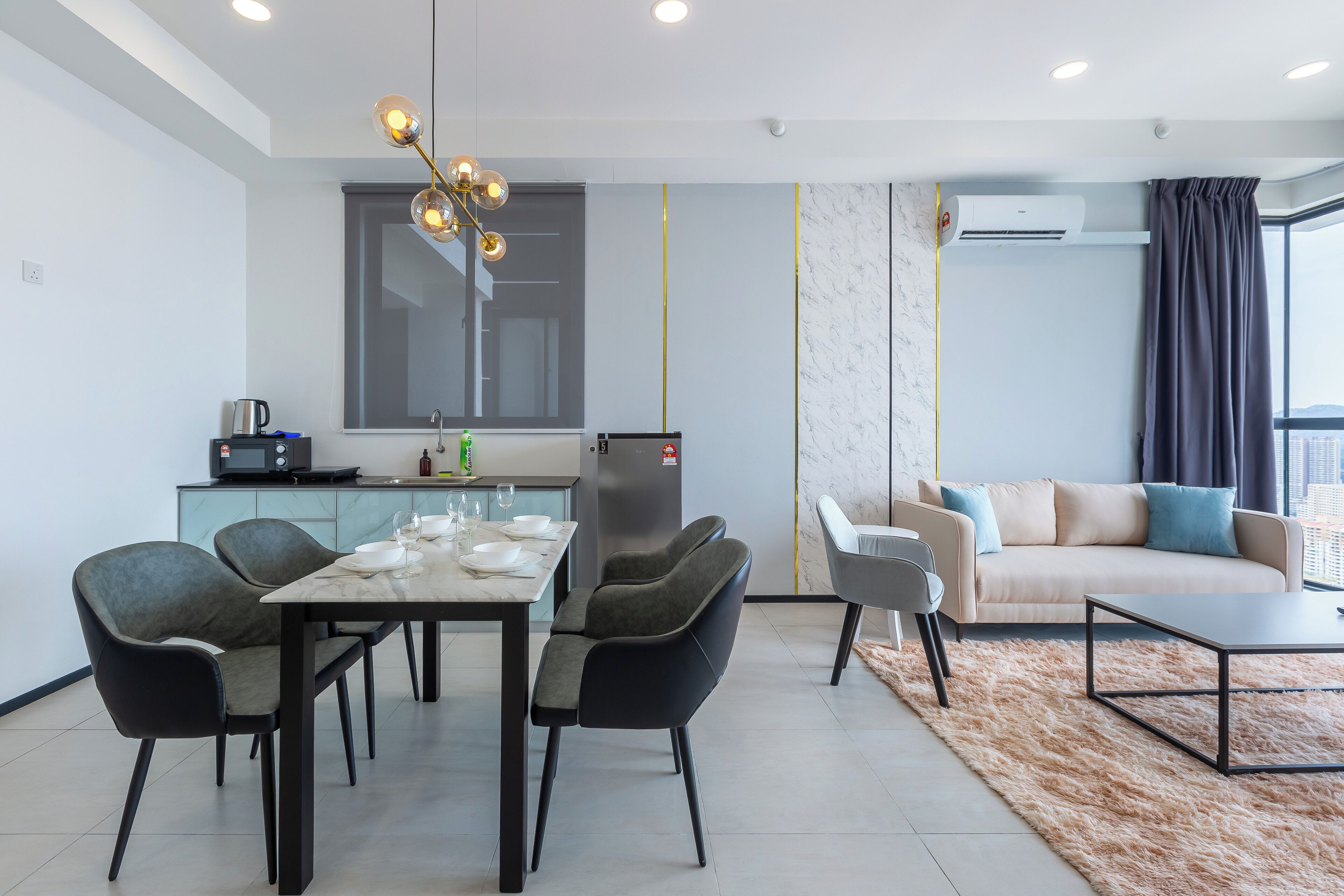 A modern living room with a sofa, a dining table with chairs, a coffee table, and a kitchen area with appliances.