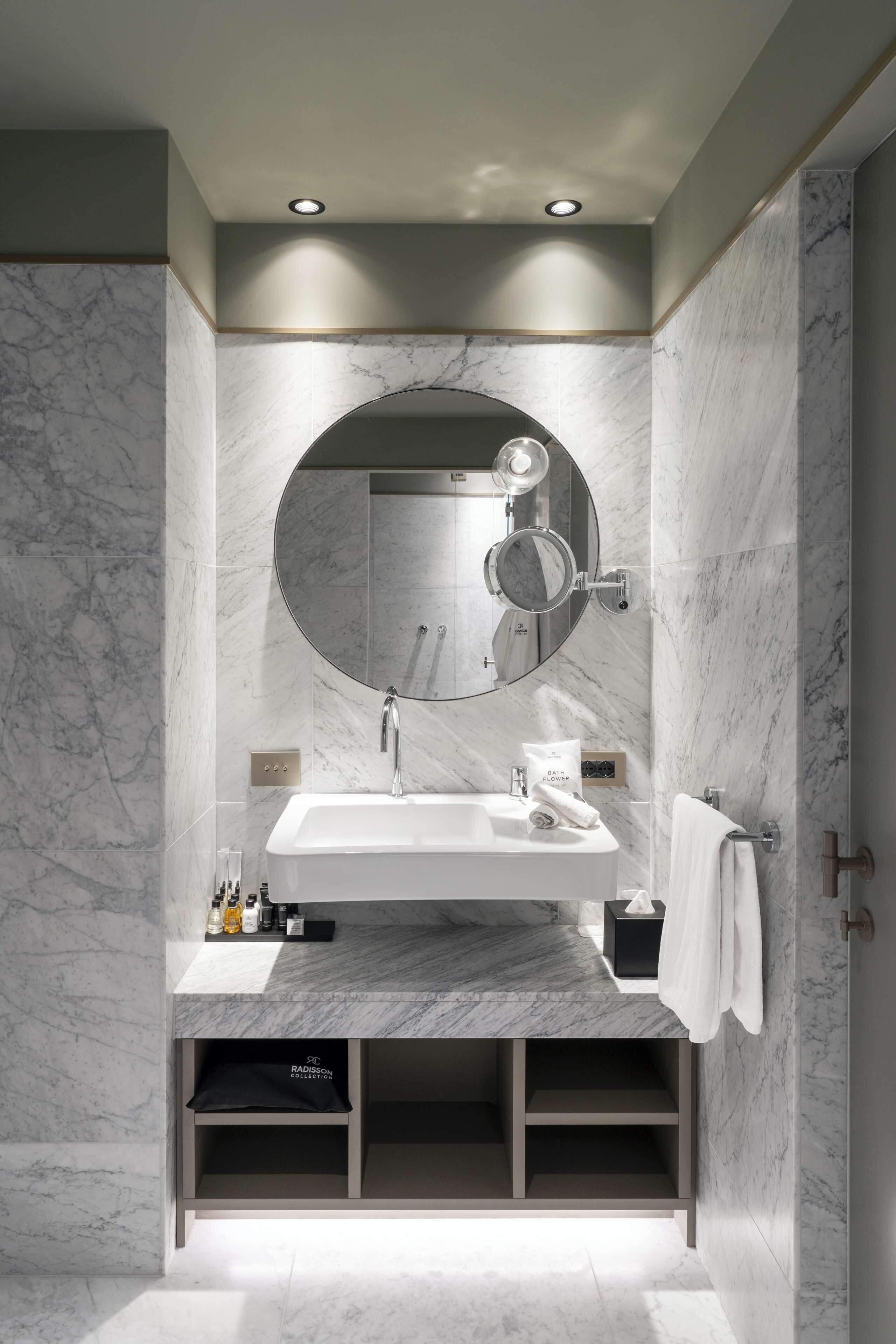 Une salle de bain moderne avec un lavabo en marbre, un grand miroir et des étagères intégrées.
