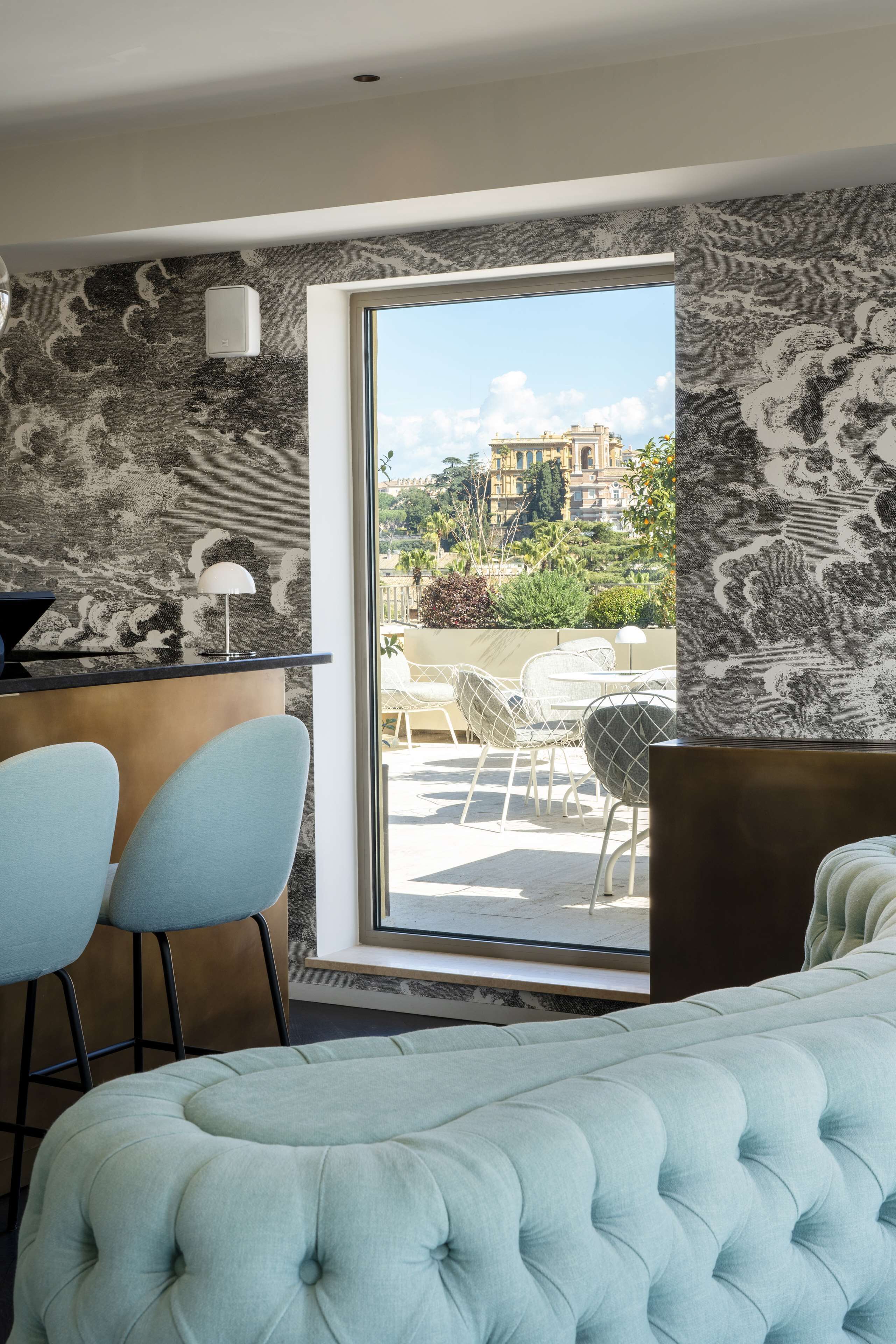 A modern hotel room with a large bed, a desk with two chairs, and a view of the outdoors.