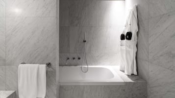 Une salle de bain moderne avec un sol et des murs en marbre, une baignoire, une douche et un porte-serviettes.