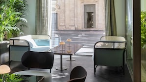 A modern hotel room with a view of a historic building, a dining area with a table and chairs, and potted plants. - Radisson Collection Hotel, Roma Antica (Rome)