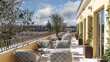 Une terrasse sur le toit avec des sièges extérieurs, une vue sur le paysage urbain et un bâtiment surmonté d’un dôme.