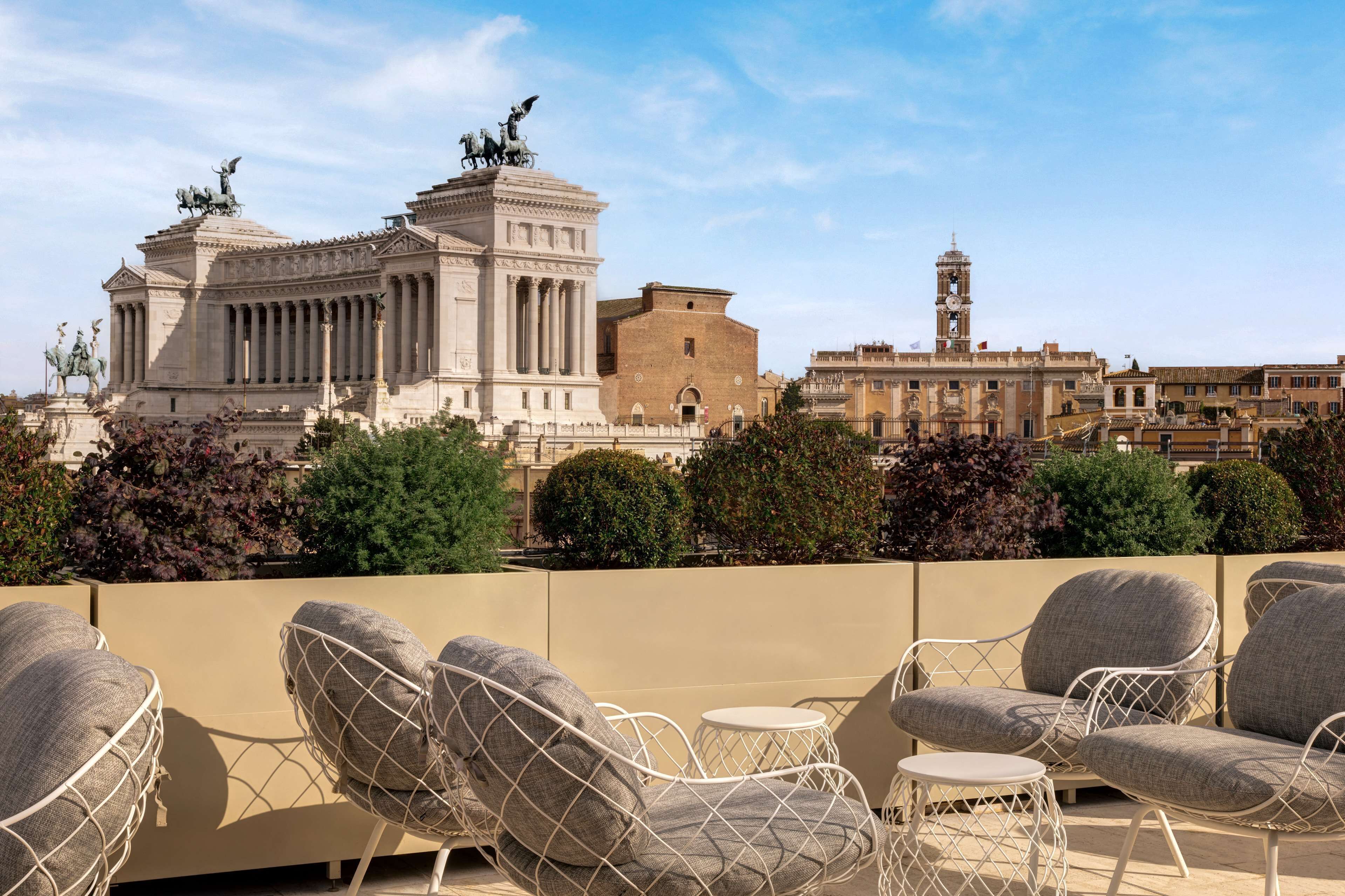 Terraza en la azotea con mobiliario exterior y vistas a edificios históricos.
