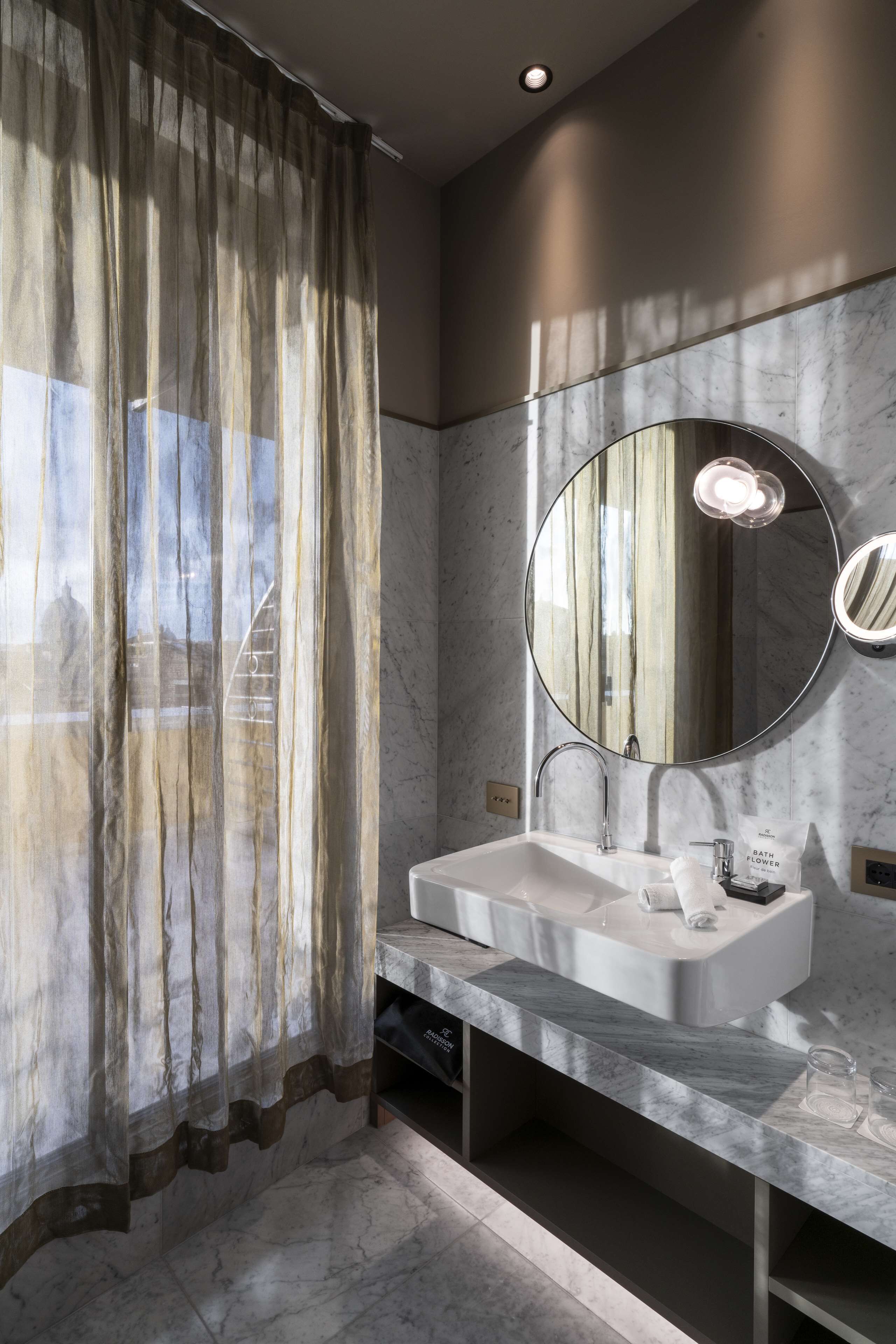 Un baño moderno con lavamanos de mármol, un espejo grande y una cortina de ducha.