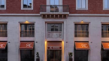 A building with a brick facade, numbered windows, and awnings with a logo.