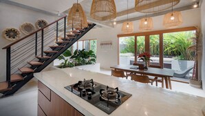 A modern kitchen with a central island, a staircase, and pendant lighting.