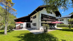 Ein zweistöckiges Gebäude mit Balkon, Außenbestuhlung und einem gepflegten Rasen.