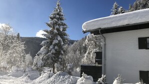 Paisaje nevado con un edificio de fachada blanca y techo negro.