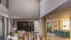 Un vestíbulo espacioso con techo alto, candelabros modernos y una recepción.