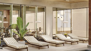 Un moderno espacio de spa con sillones reclinables, una planta grande en maceta y una máquina de pesas.
