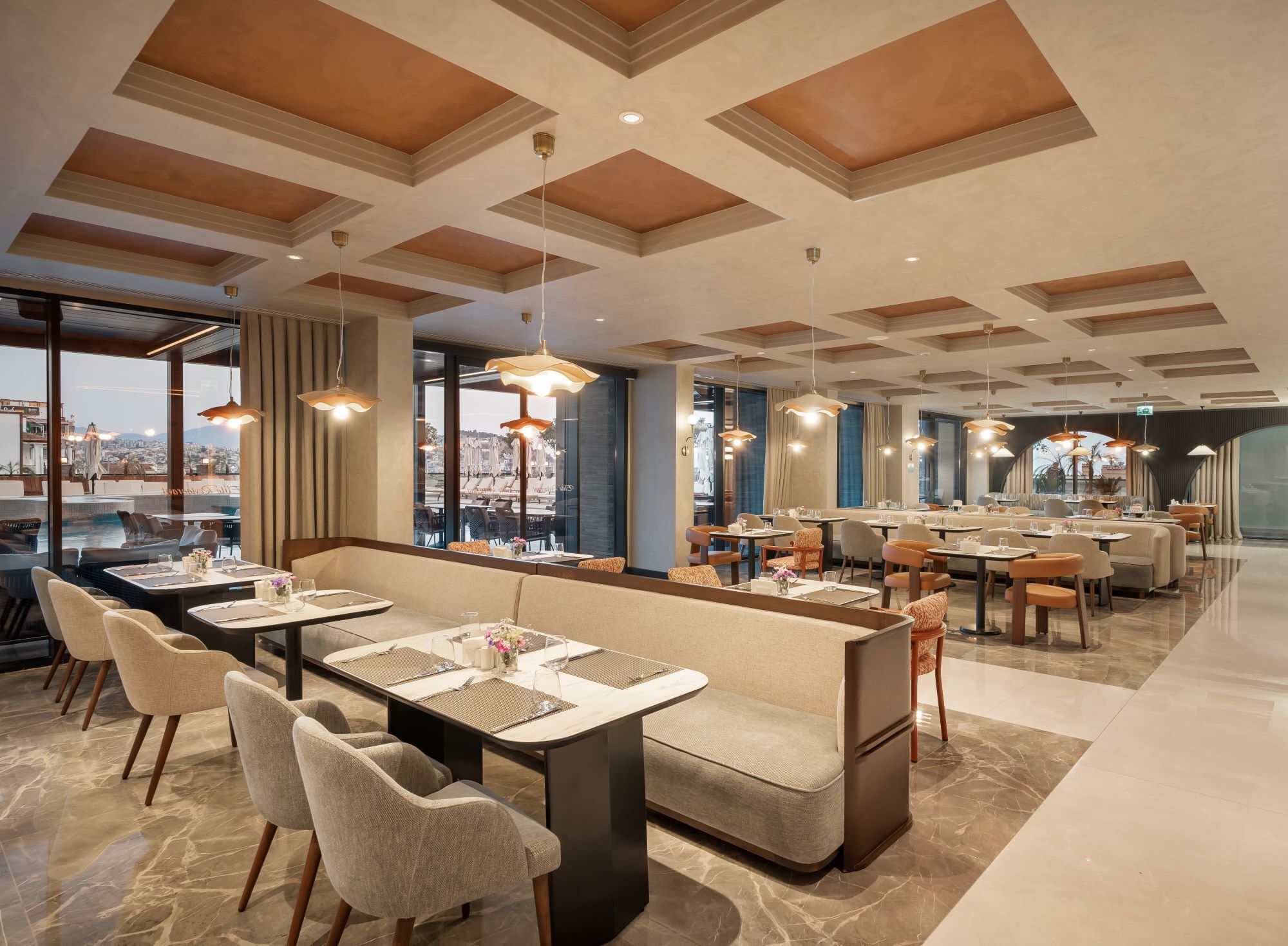 A modern dining area with high ceilings, large windows, and a variety of seating arrangements including booths and tables.
