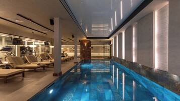 A swimming pool with lounge chairs and a spa area.