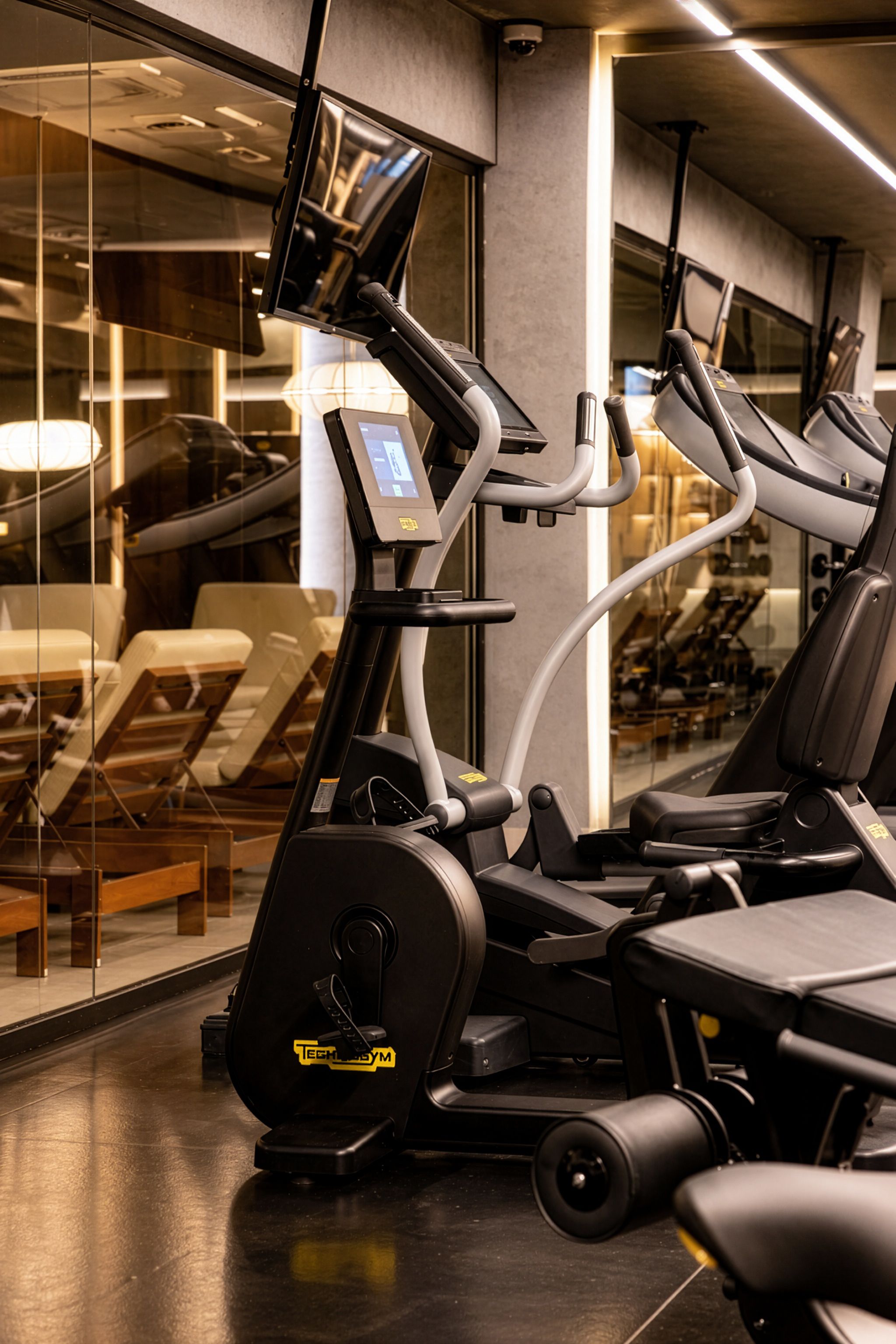 Een fitnessruimte met cardioapparatuur, een loopband en een hometrainer.