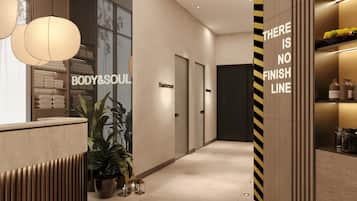 Een moderne hotel lobby met een receptiebalie, een plant en een muur met een 'BODY&SOUL' bord.