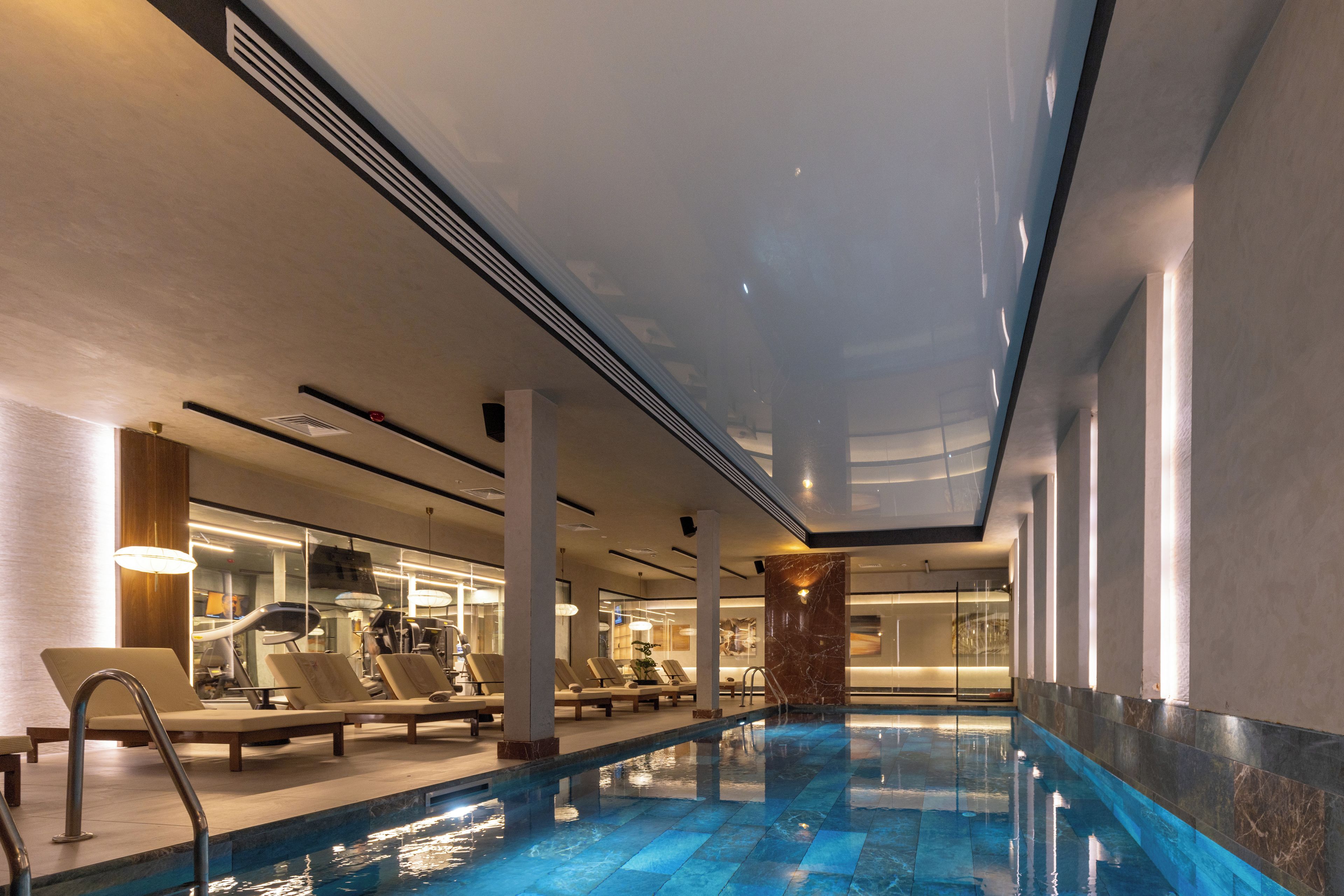 Una piscina interior con sillas de descanso y equipo de ejercicio.