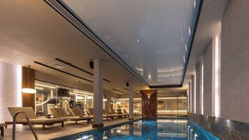 Una piscina interior con sillas de descanso y equipo de ejercicio.