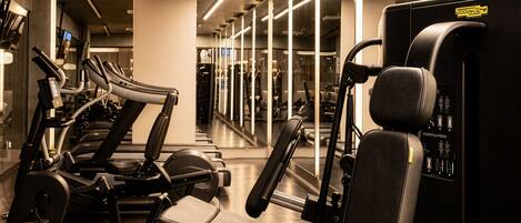 A gym with exercise equipment, mirrored walls, and a modern design.