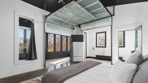 A modern bedroom with a large bed, a skylight, and a view of the outdoors. - Unique Modern Ranch with Pool, Hot Tub, Grill & Fireplace (Nashville)