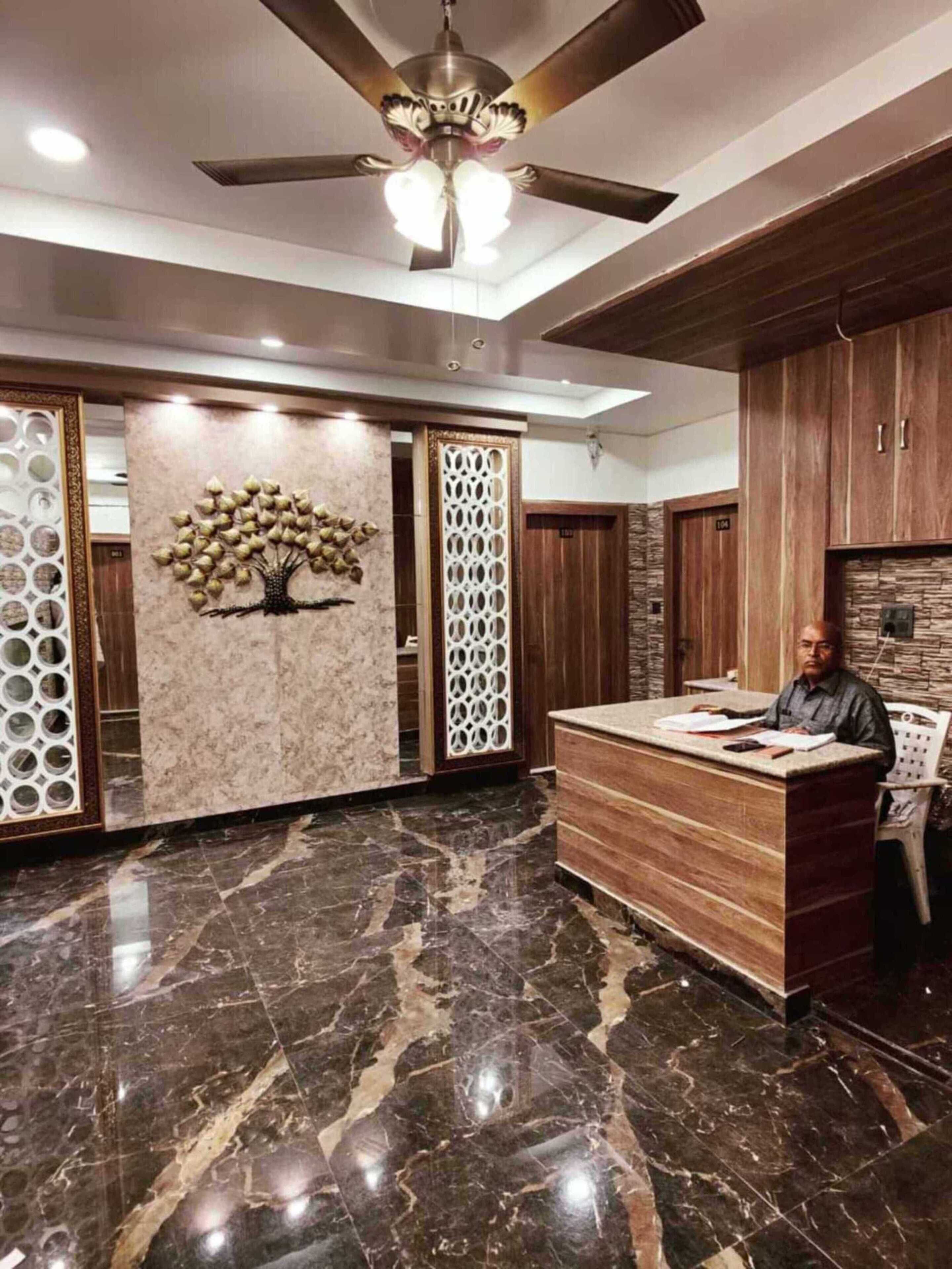 A reception area with a marble floor, a wooden reception desk, and a decorative tree mural.
