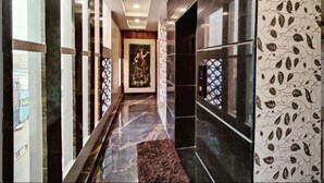 A hallway with marble flooring, a patterned wall, and a framed artwork on the wall. - Hotel Royal Vrindavan (Aligarh)