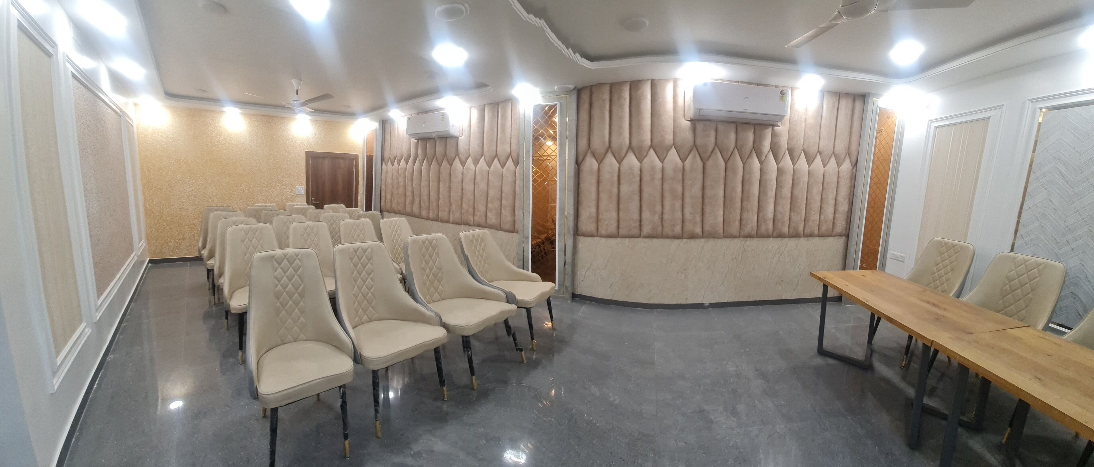 A conference room with rows of chairs, a wooden table, and a ceiling fan.